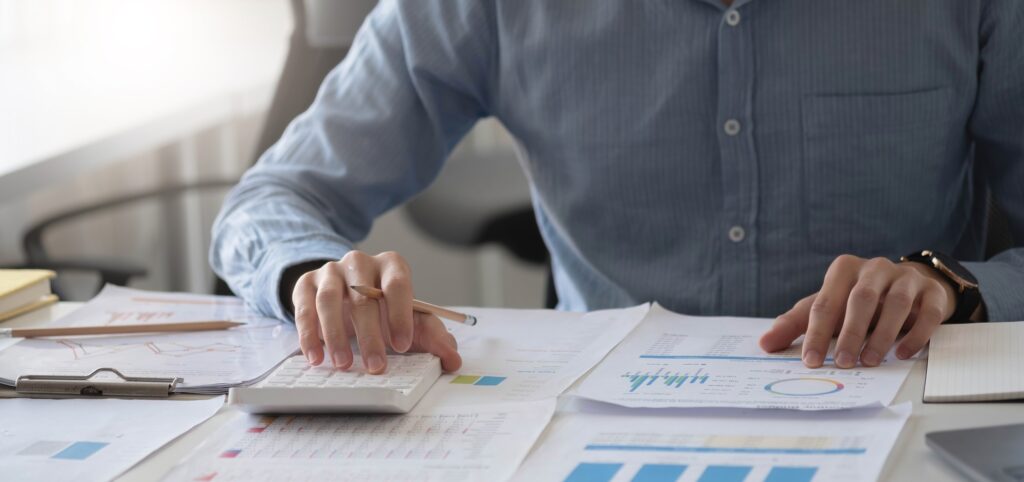 Close up businessman hand using calculator and working with laptop calculate about finance